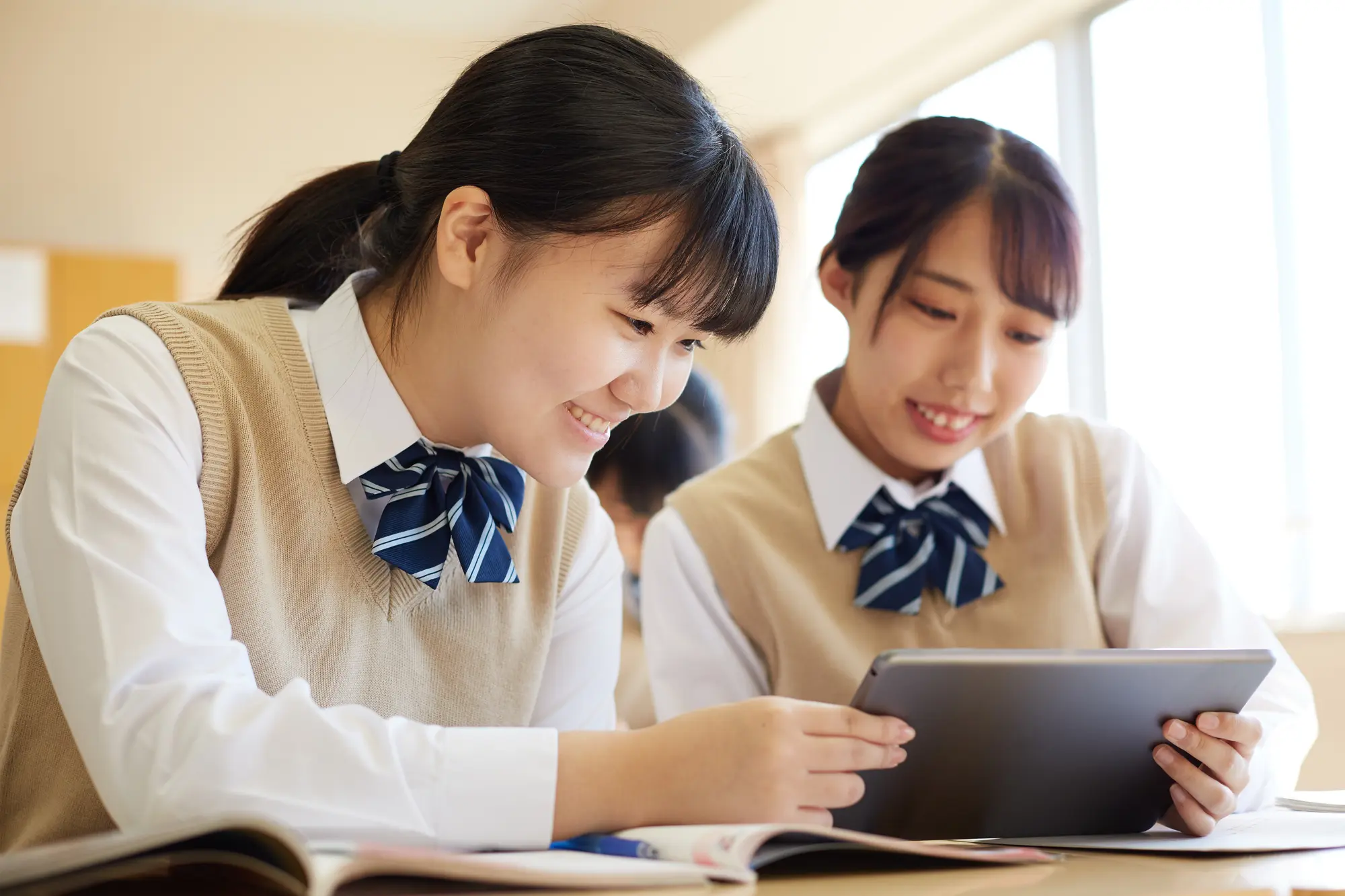 タブレットを使って笑顔で学習する生徒たち